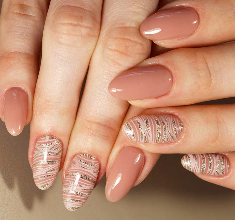 unghie dalla forma a mandorla, unghie gel color carne con alcune decorazioni con smalto bianco e glitter