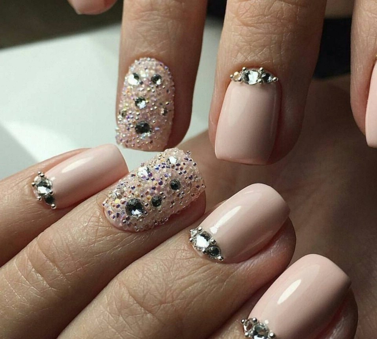 Unghie con smalto gel di colore rosa, decorazioni con brillantini e accent nail effetto sugar sul dito anulare 