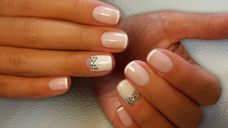 French manicure classica con decorazioni brillantini sul dito anulare 